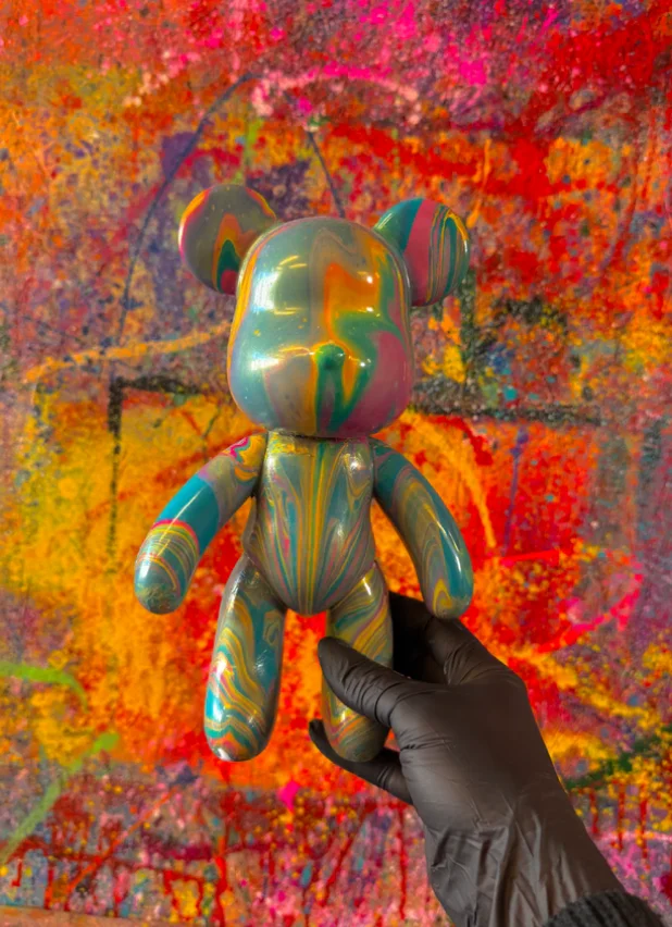 Bear sculpture with colourful marbled acrylic paint against a paint-splattered studio wall